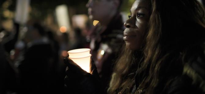 Black woman at a vigil holding a memorial candle