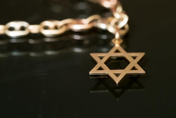 gold star of David on chain, on reflective black surface