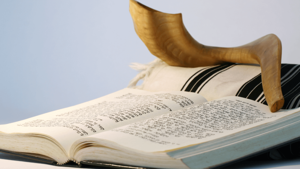 Open prayer book with a shofar and prayer shawl