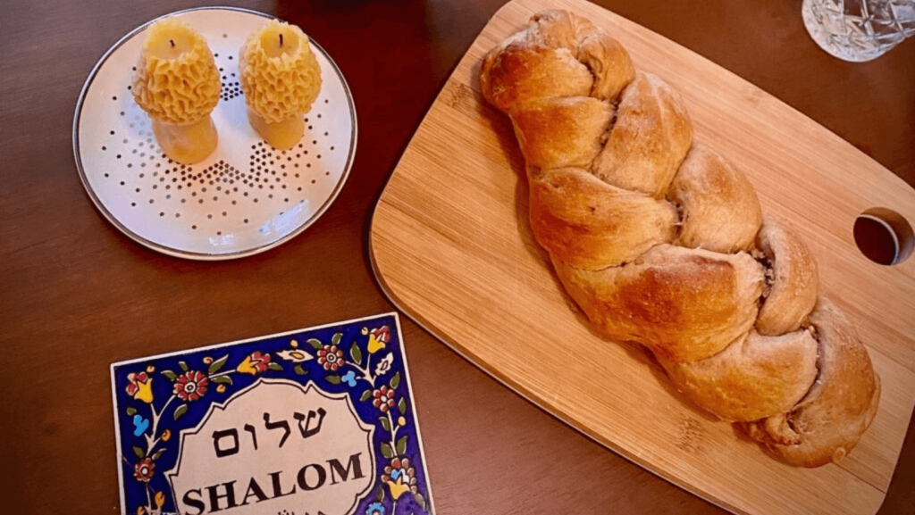 Challah on a serving platter, apples, and a plaque with Hebrew print
