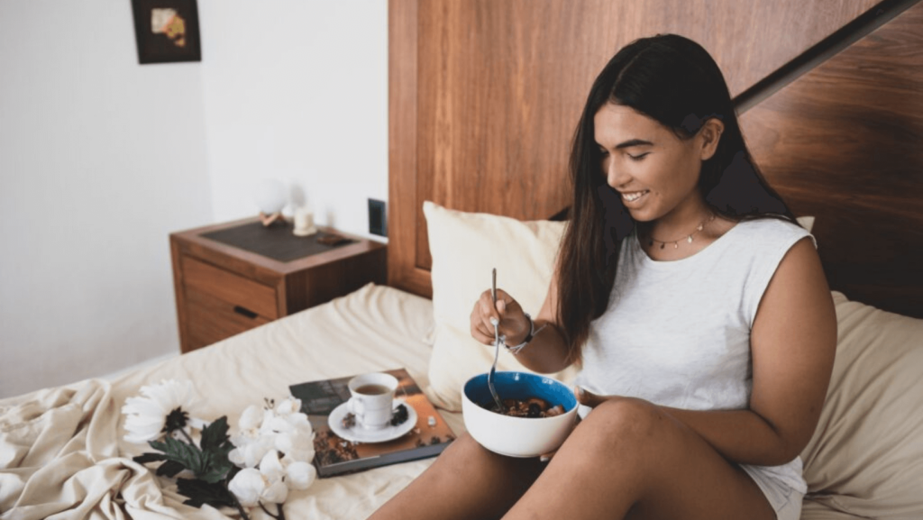Woman in bed eating fruit out of a white bowl