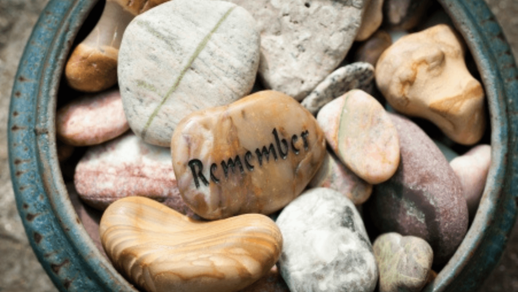 A collection of small stones, one engraved with the word "Remember"