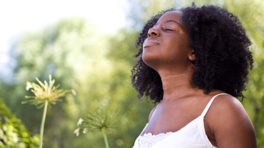 Black woman outside with eyes closed looking up