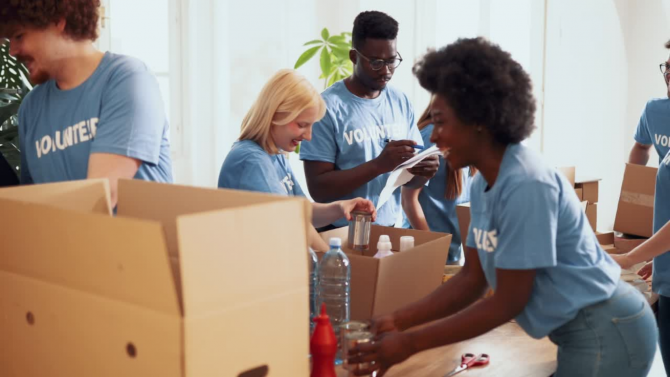 Volunteers at a food bank packing boxes of bottled water and canned goods